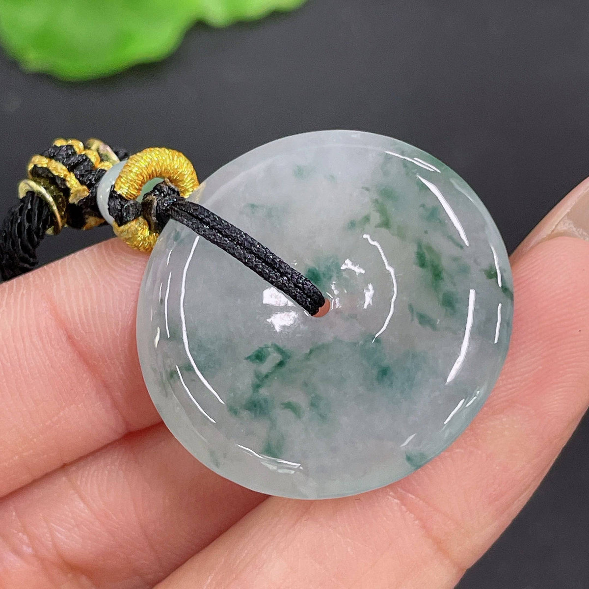 Huiliu jadeite pendant featuring a peace knot design on a cord, crafted from high-quality green jade, certified by HUILIU HQ.