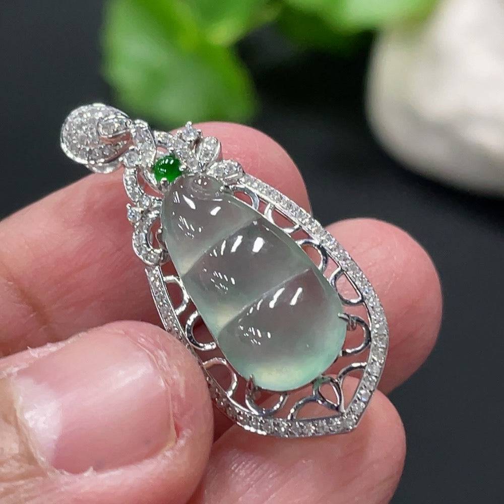 Jadeite blessing bean pendant with 18K gold setting and diamond accents, displayed against a neutral background.