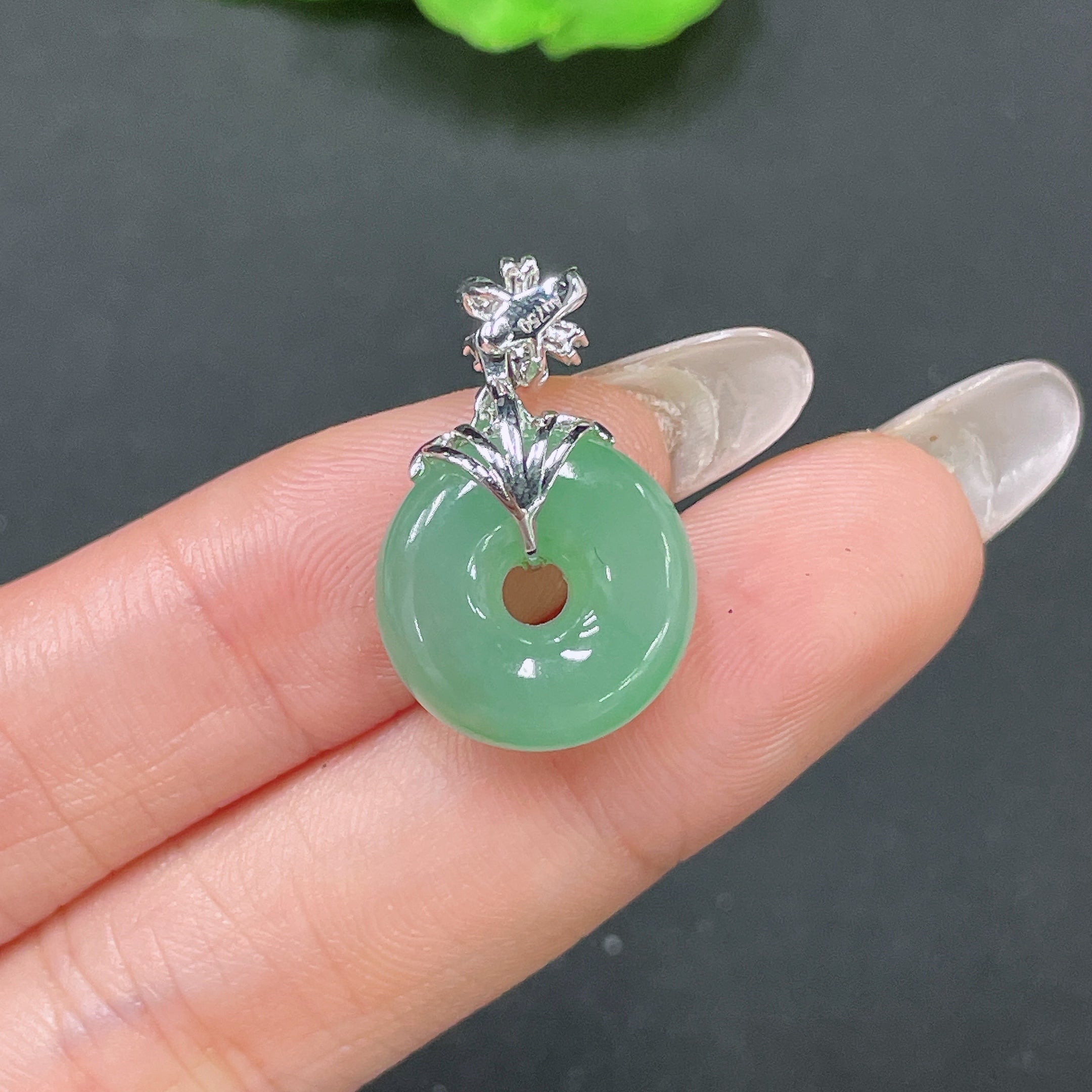 Jadeite pendant with peace knot design, 18k gold inlay, and diamond accents, featuring a polished jade surface and intricate craftsmanship.