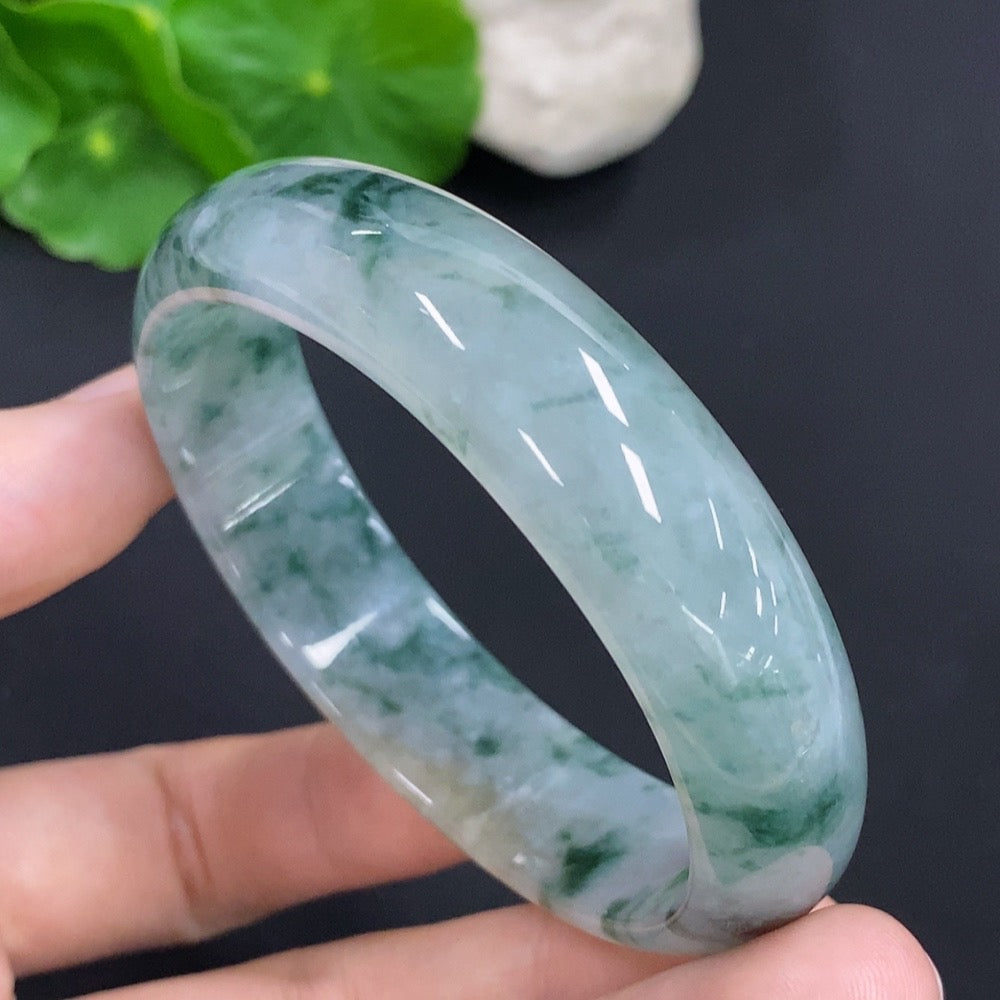 HKHQ jadeite oval bangle in size 58.8 with a polished surface, showcasing its elegant green hue and smooth oval shape.