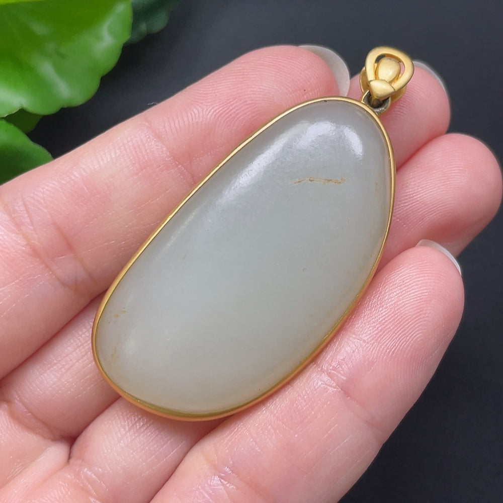 Hetian jade inlaid pendant on 18K gold chain, HKHQ necklace featuring a smooth, polished jade stone with intricate gold detailing.