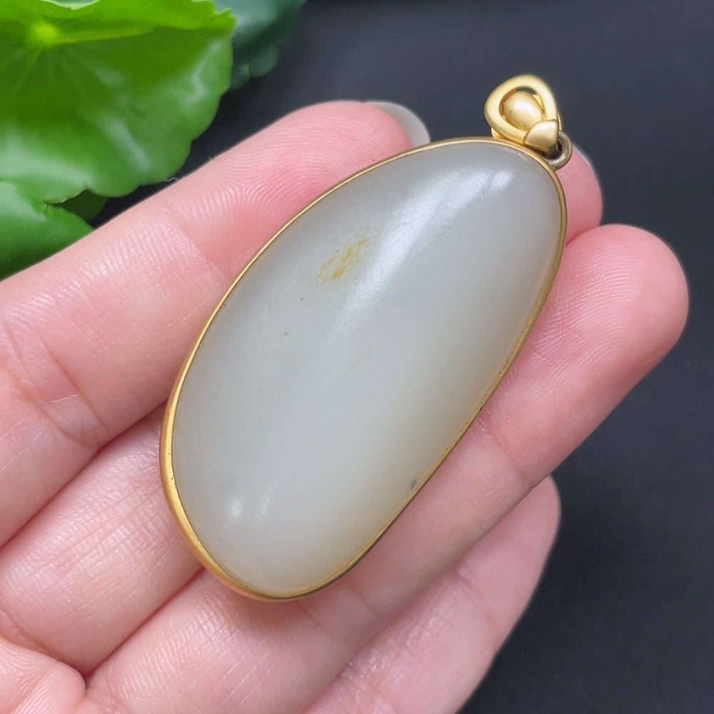 Hetian jade inlaid pendant on 18K gold necklace, featuring intricate craftsmanship and a polished jade stone, worn as jewelry.