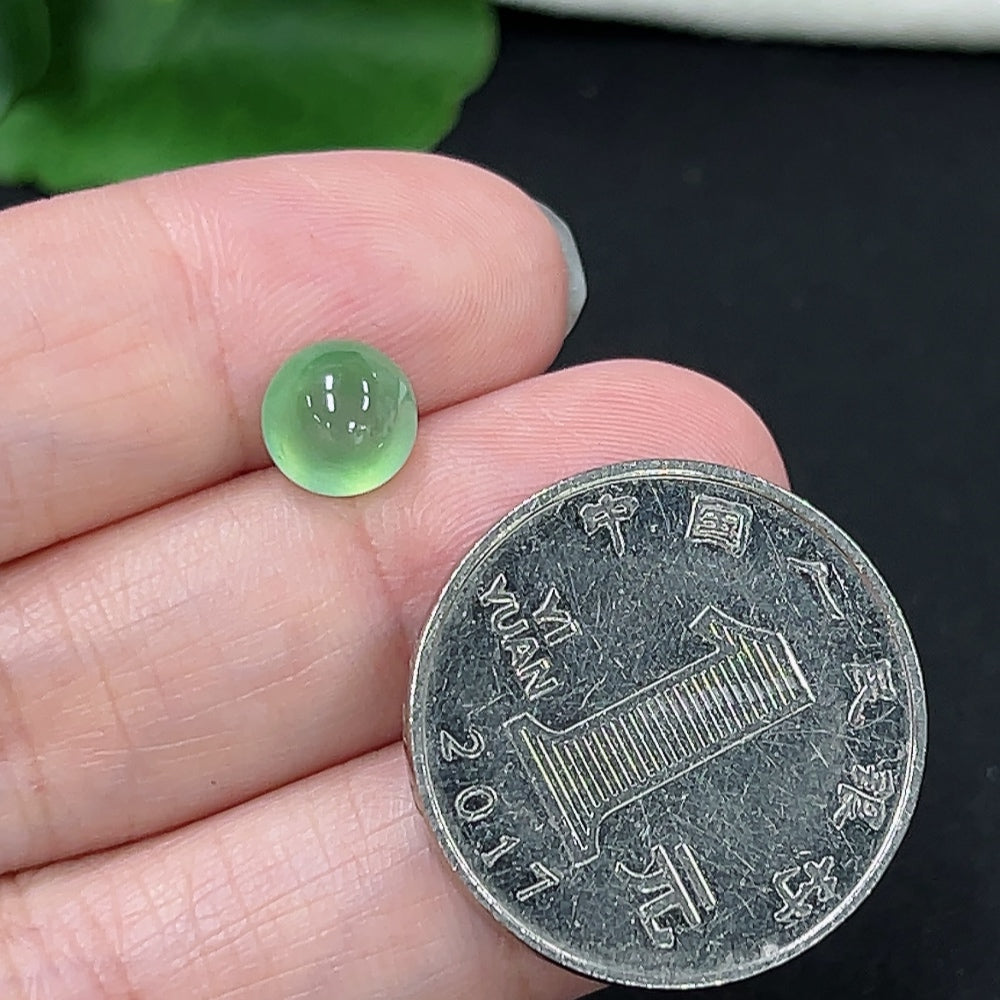 Close-up of a green jadeite cabochon jewelry piece, weighing approximately 0.3g, with smooth, polished surface and natural color.