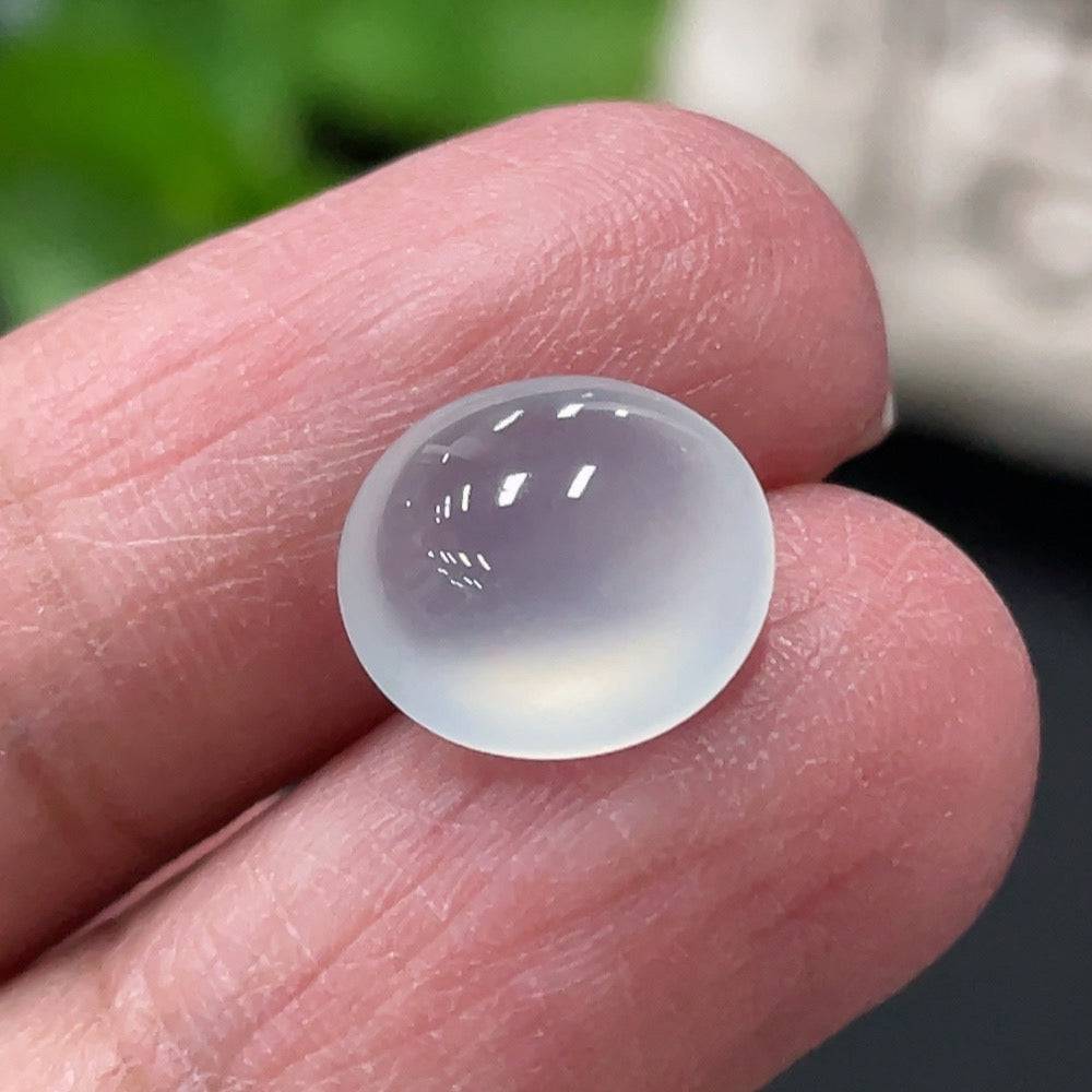 Jadeite cabochon gemstone from HUILIU HQ, weighing approximately 0.73g, with smooth, polished surface and vibrant green color.