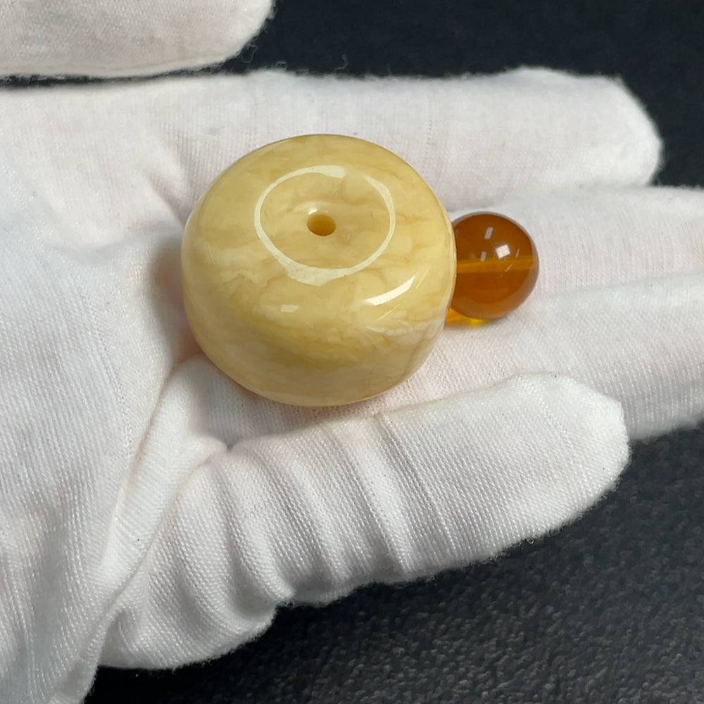 Huiliu certified amber beeswax pendant showing warm amber hues and natural textured surface, photographed on a neutral background.