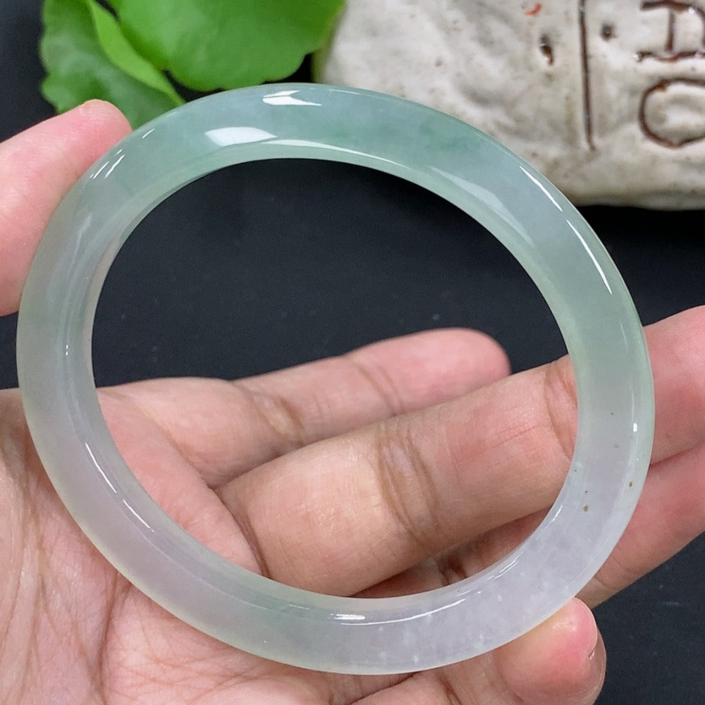 HKHQ jadeite oval bangle in size 55.3 with a 24.3g weight, showcasing smooth, polished green jadeite on a white background.