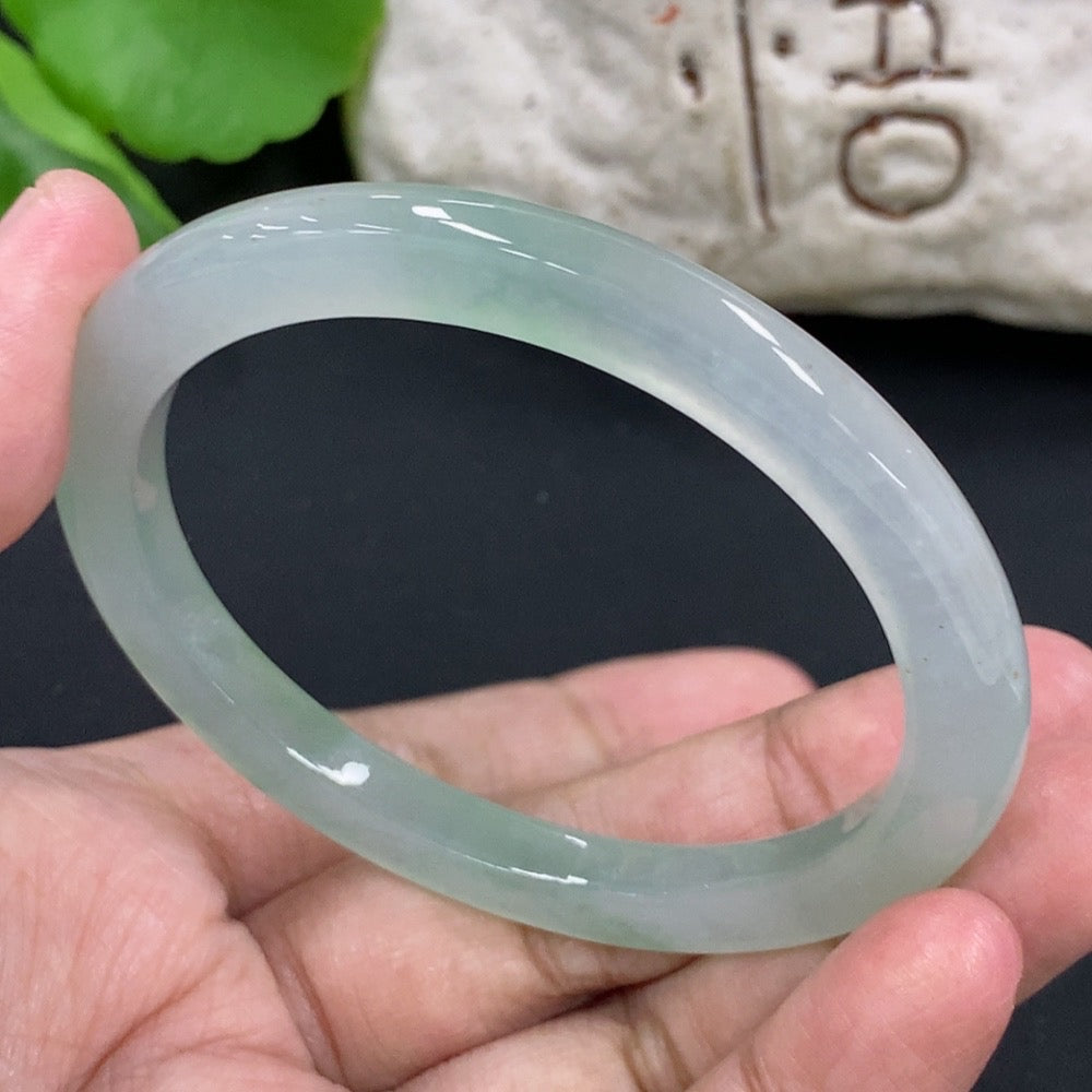 HKHQ jadeite oval bangle in size 55.3 with 24.3g, showcasing smooth, polished green jadeite bracelet on a neutral background.