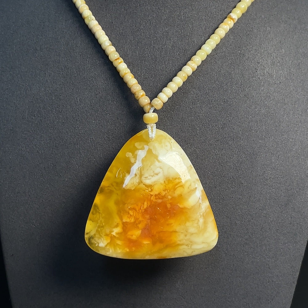 Amber beeswax pendant with colorless coating, partial repairs visible, HKHQ brand, weighs about 35.77g, shown with a collection certificate