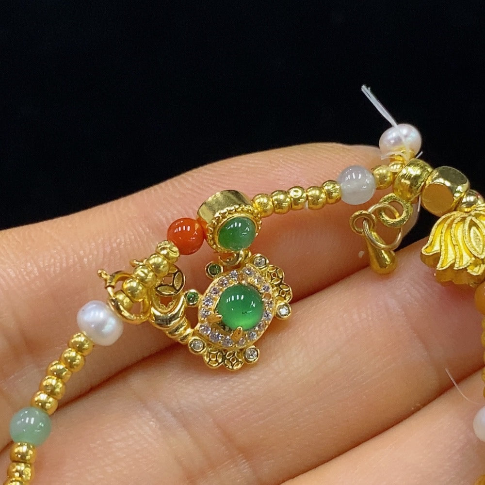 HUILIU HQ Jadeite inlaid bracelet with red beads, gold accents, small beads, and undetermined color origin on unmarked surface.