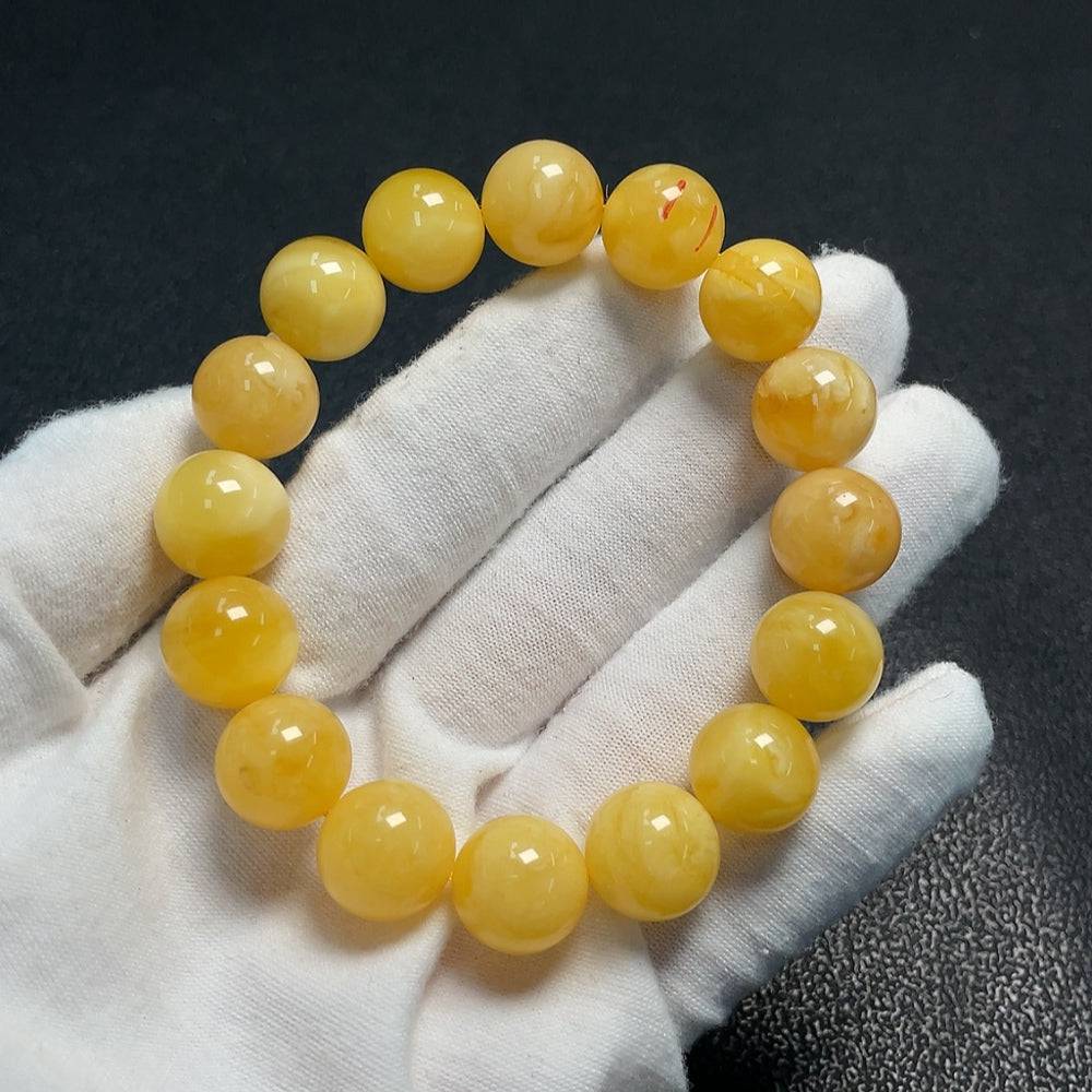 Amber beeswax bracelet by HUILIU HQ, approximately 12.6mm, with visible repairs, showcasing warm amber tones and handcrafted details.