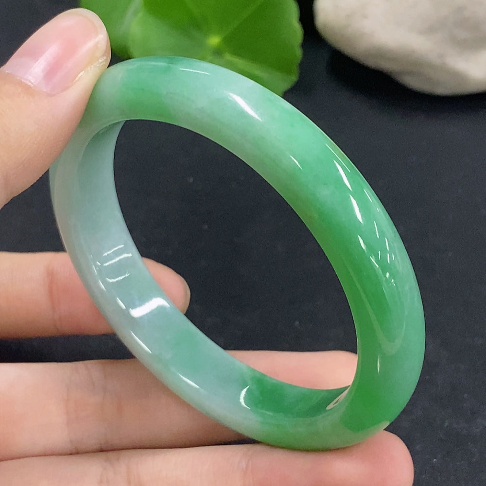 HKHQ jadeite oval bangle in size 53.5 with 38.88g, showcasing smooth, polished green jadeite bracelet on a plain background