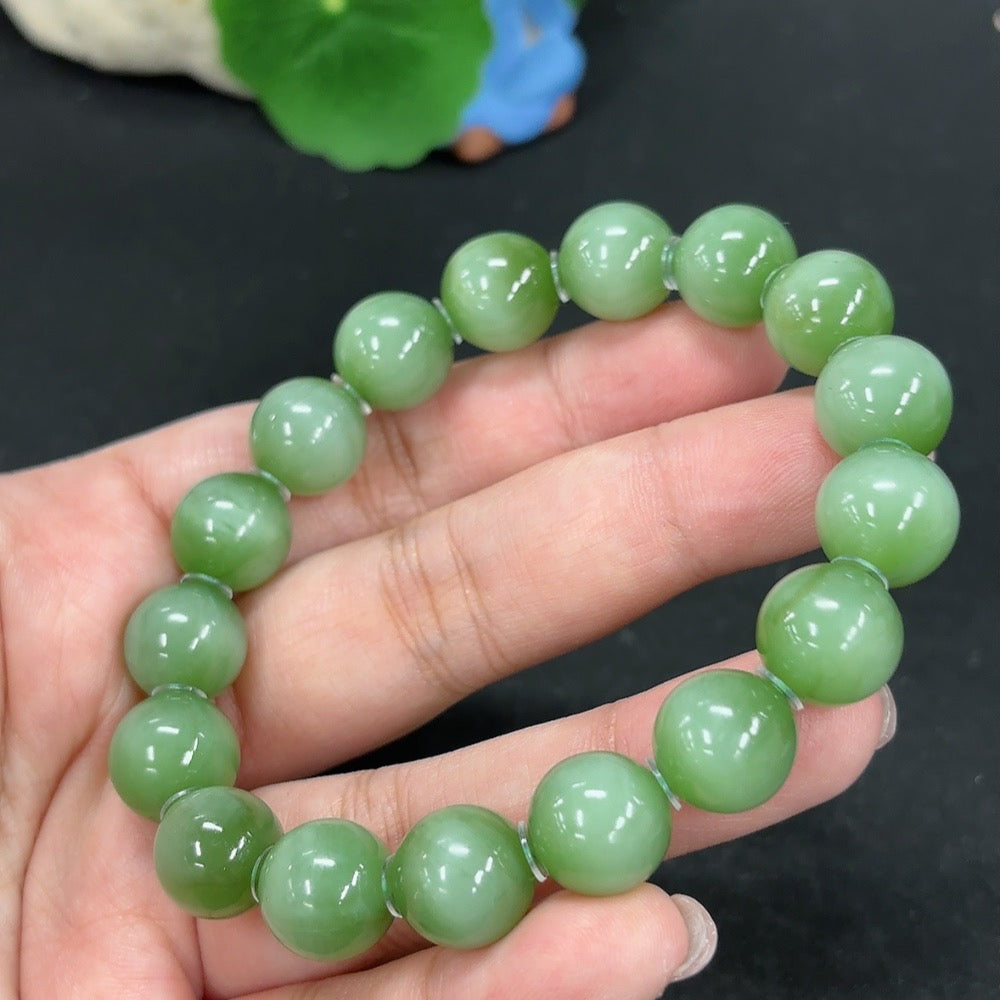 Green Hetian Jade bracelet from HKHQ featuring smooth, polished jade beads strung together on an elastic band.