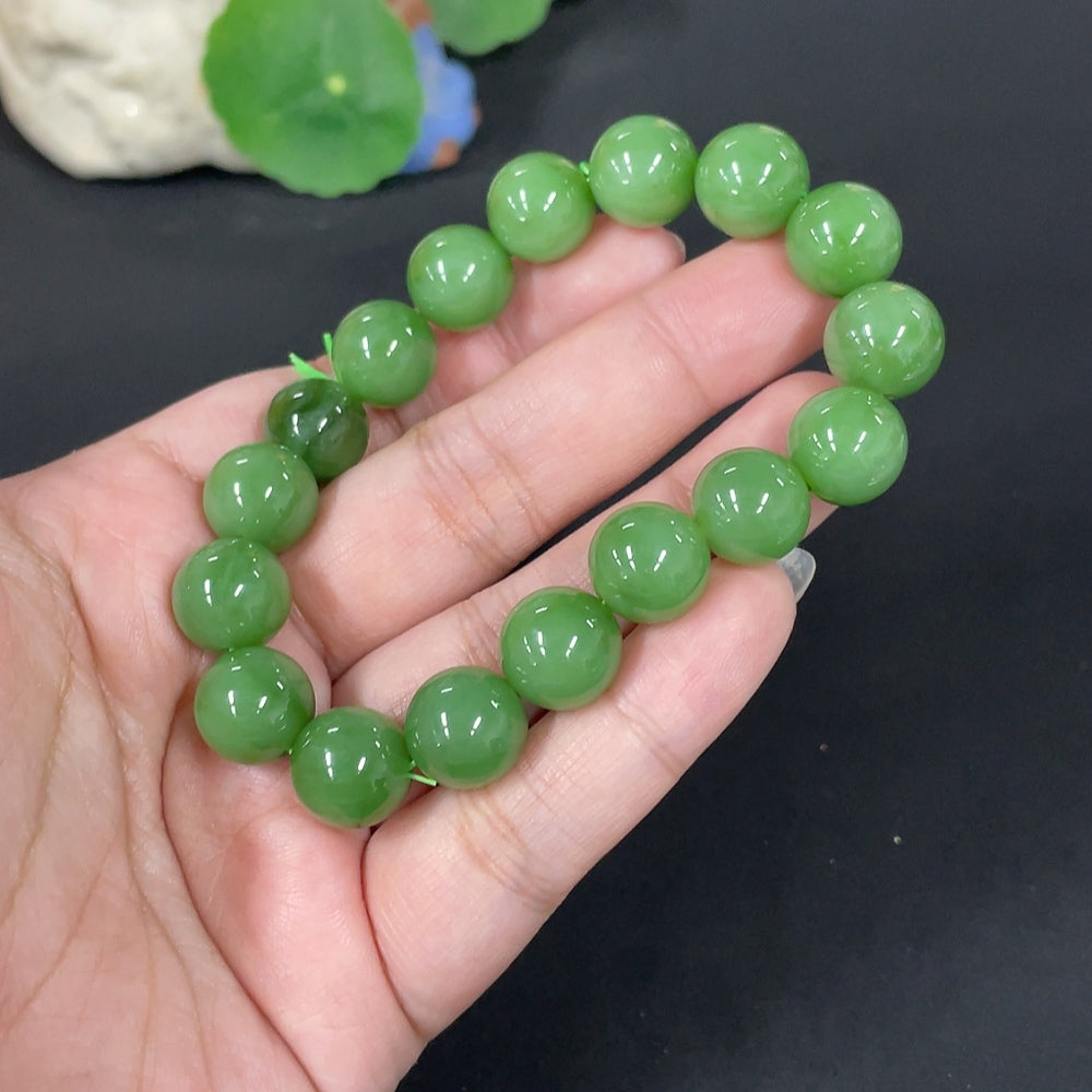 Huiliu Hetian jade bracelet with 11.8mm smooth green jade beads, certified by Huiliu, resting on a neutral background.