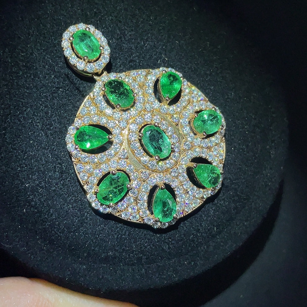 Emerald pendant with 18K gold setting, clarity enhanced, featuring a vibrant green gemstone on a necklace.