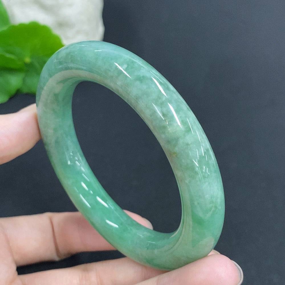 Huiliu certified jadeite round bangle showcasing smooth, polished green jade with a glossy finish, worn on a person's wrist.