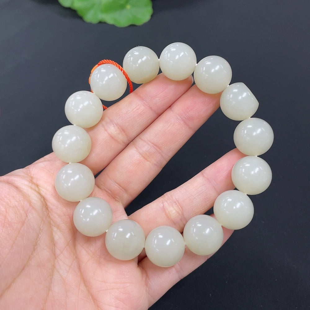 HKHQ Hetian Jade bracelet with 13.9mm beads, weighing 64.2g, featuring smooth jade stones on a natural skin tone background.