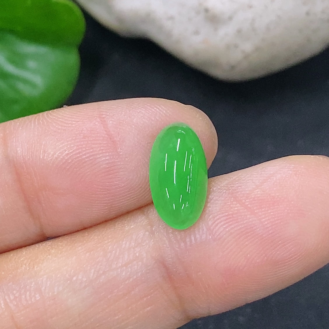 Bright green jadeite cabochon jewelry piece, 0.43g, showcasing smooth, polished surface and natural gemstone beauty.
