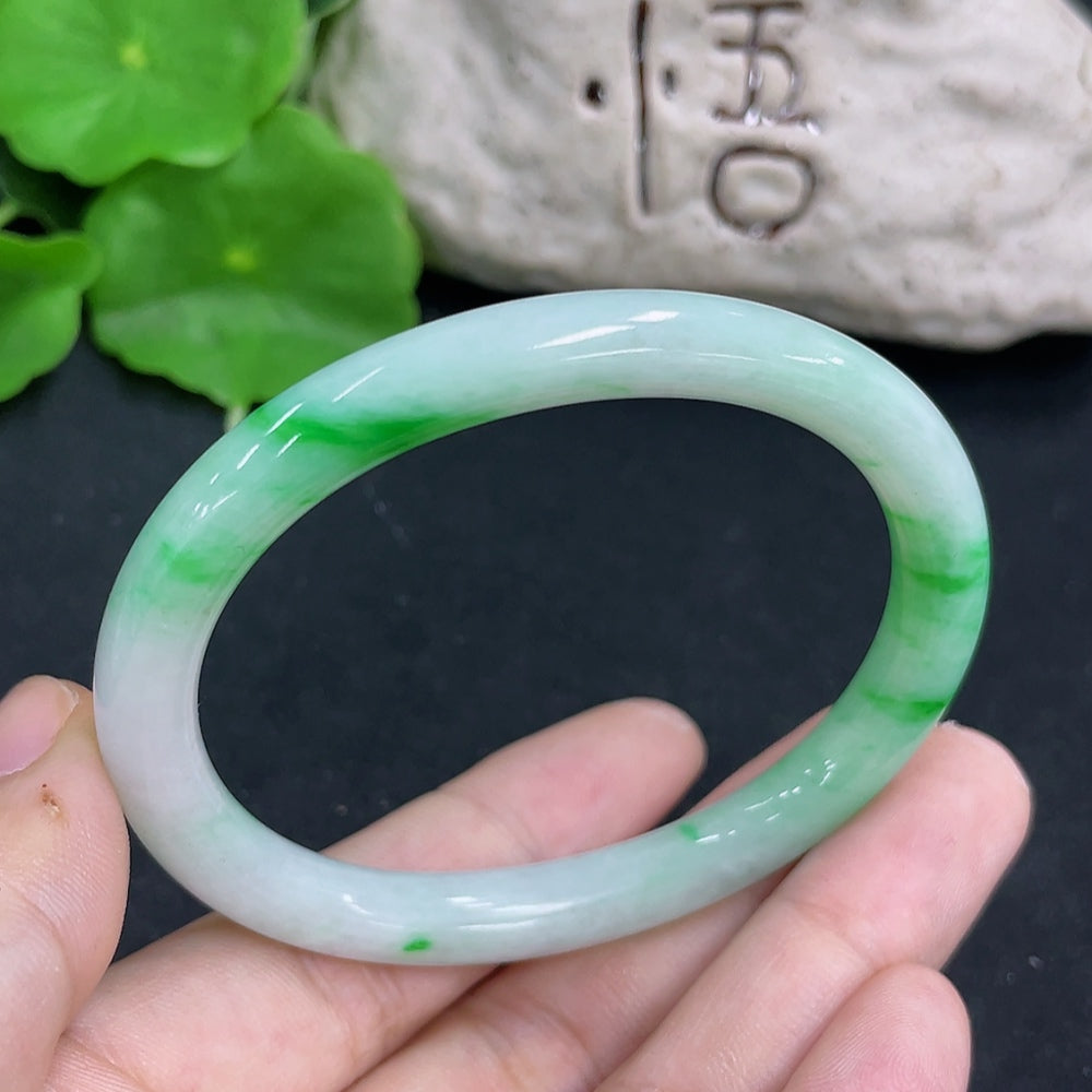 HKHQ jadeite oval bangle in size 54.2 with a polished green surface, weighing 25.8 grams, displayed on a plain background.
