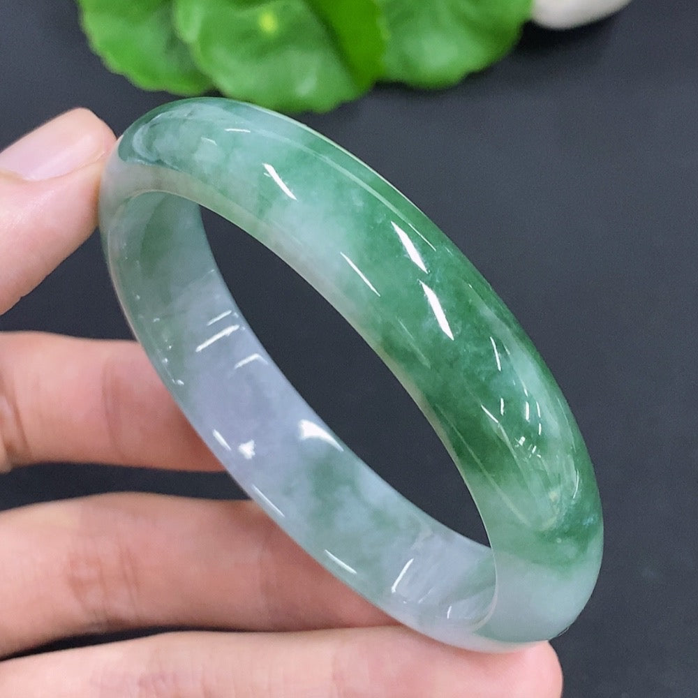 HKHQ jadeite oval bangle in size 53, weighing 38.1g, showcasing smooth, polished green jadeite bracelet on a plain background.