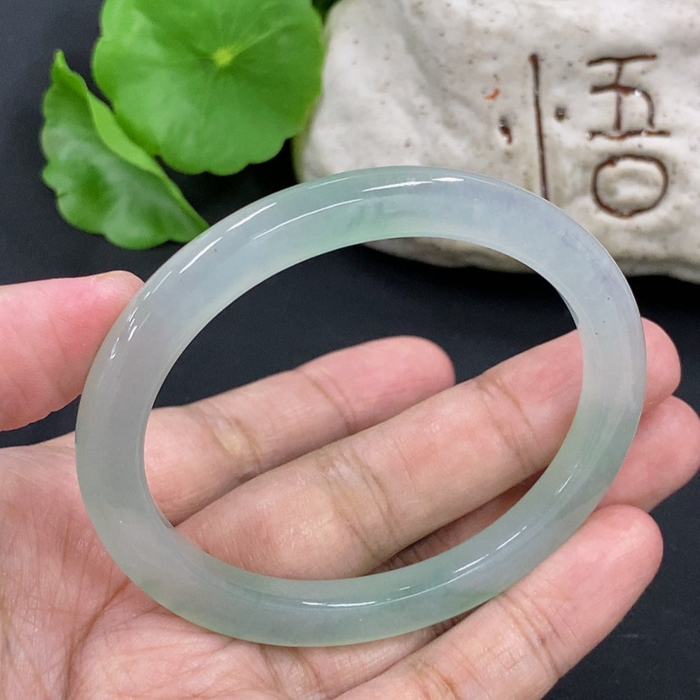 HKHQ jadeite oval bangle in size 55.3 with 24.3g, showcasing smooth, polished green jadeite bracelet on a neutral background.