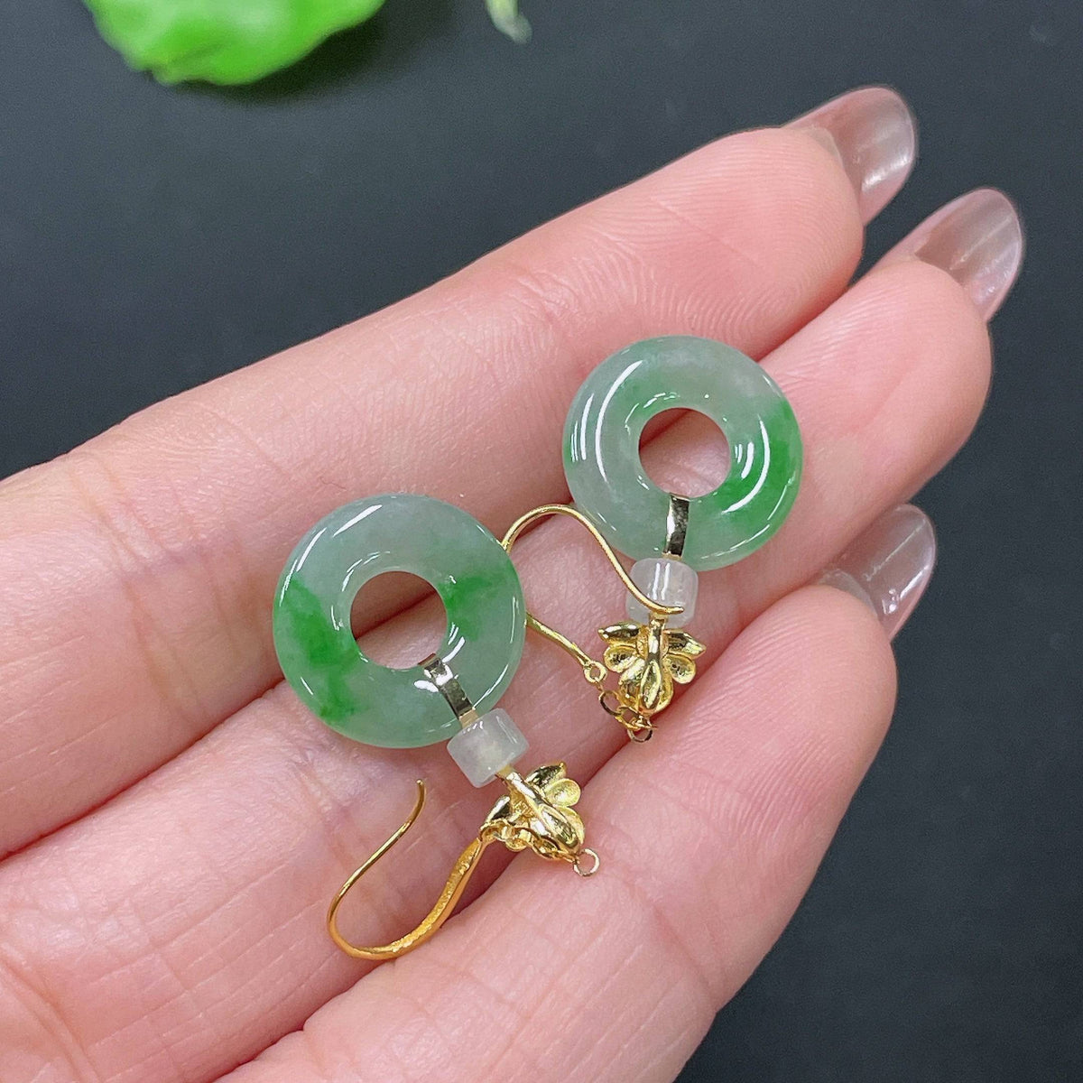 Huiliu Certified Jadeite earrings featuring smooth, polished green jade stones with gold-tone hooks.