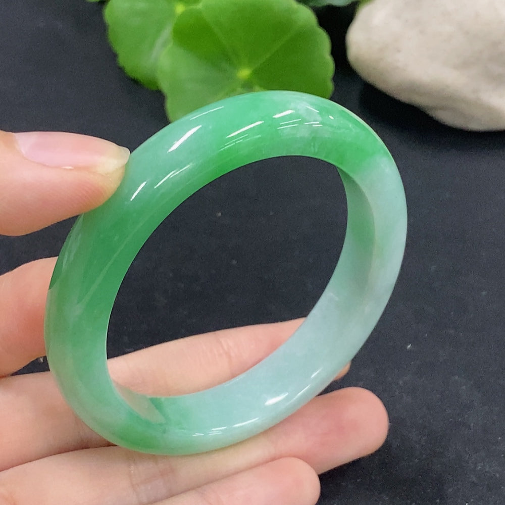 HKHQ jadeite oval bangle in size 53.5, showcasing smooth, polished green jade with elegant oval shape and natural stone texture.