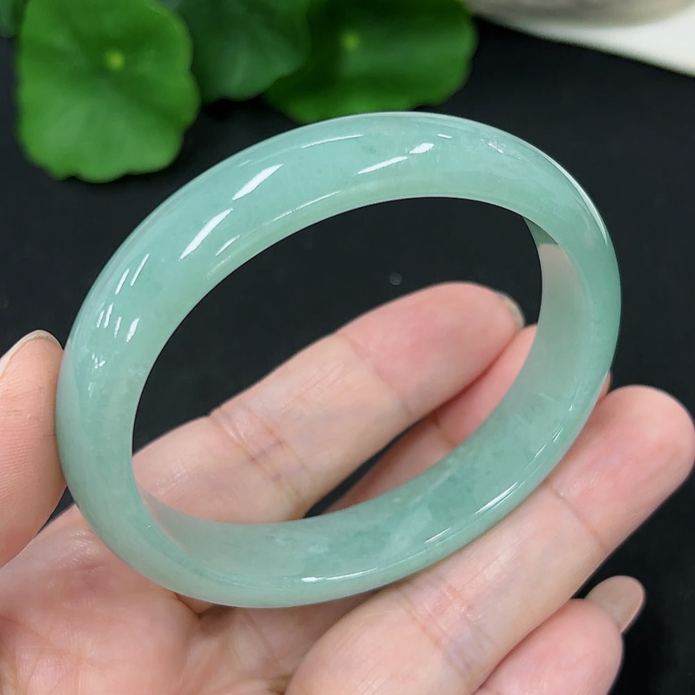 HKHQ jadeite oval bangle in size 53.2 with a polished finish, showcasing its smooth, rounded design and vibrant green color.