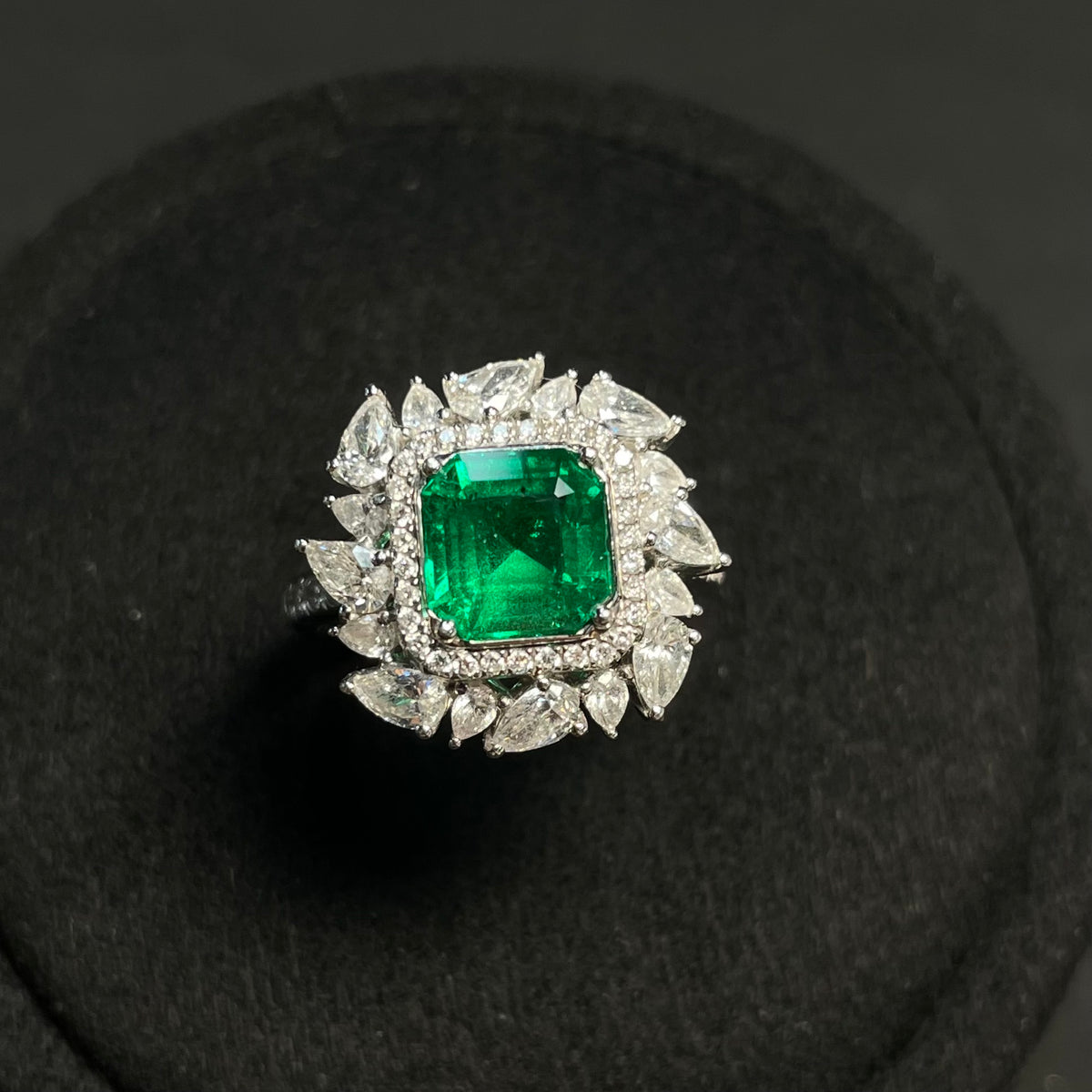 Emerald ring with diamond accents in 18K gold, featuring enhanced clarity, showcasing detailed craftsmanship and elegant design.