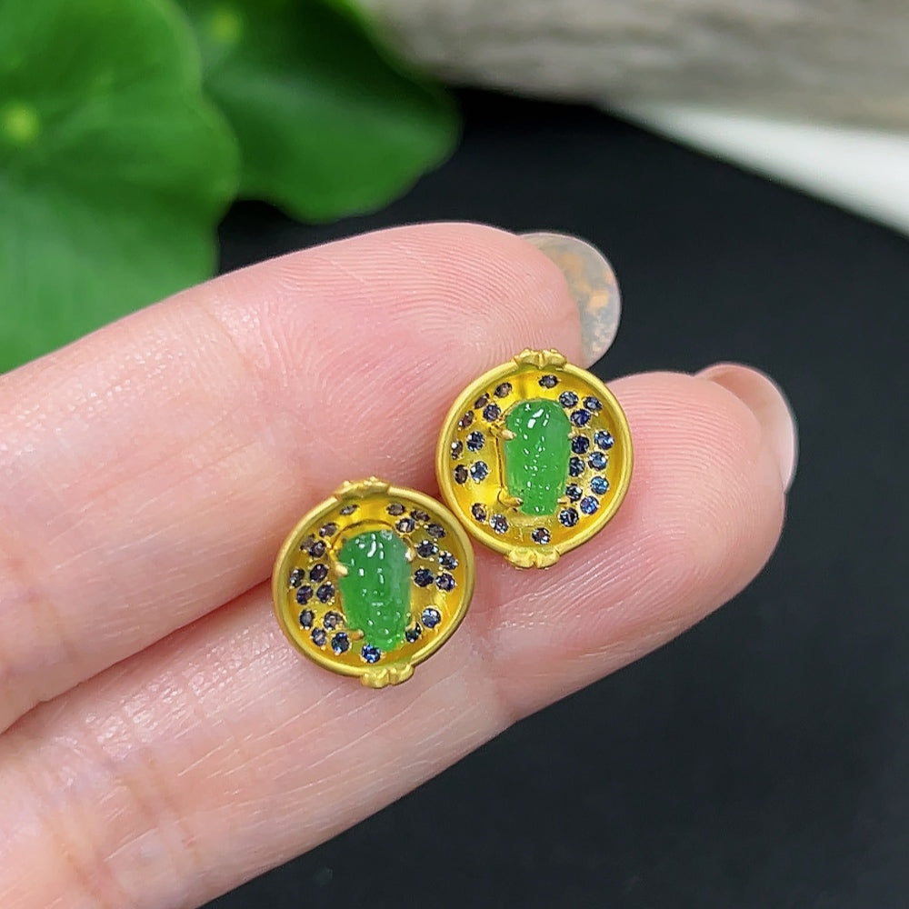 Pair of hkHQ jadeite earrings with 18K gold mounting, featuring polished green jade stones and gold earring backs.