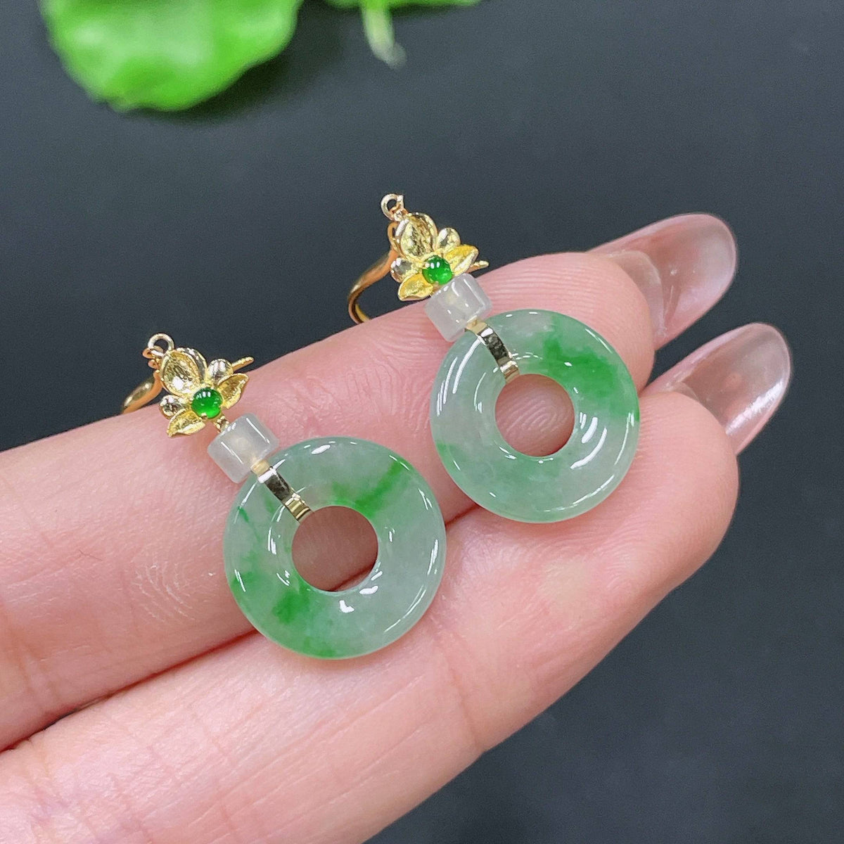 Huiliu certified jadeite earrings featuring smooth, polished jade stones with silver hooks on a white background.