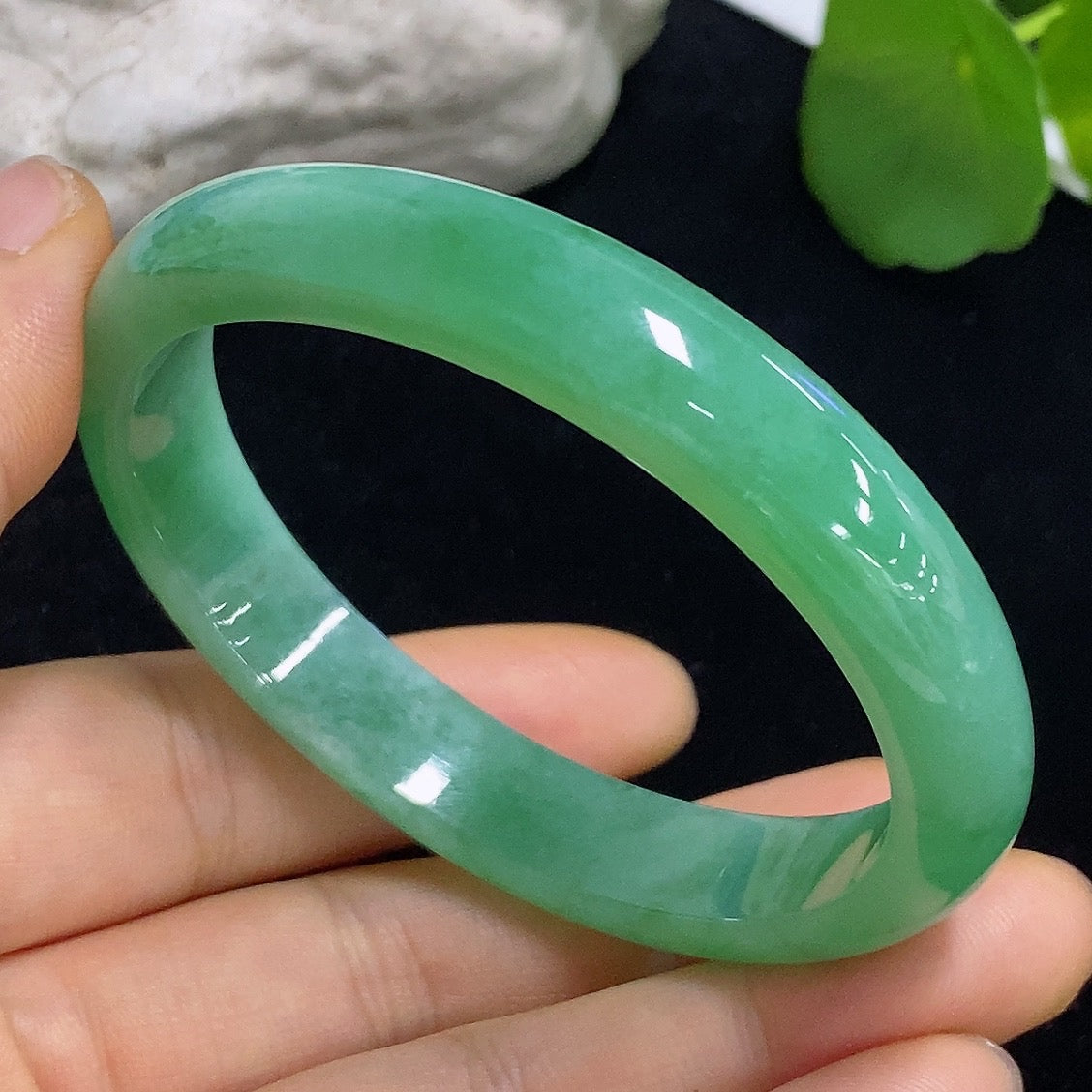 HKHQ jadeite oval bangle in size 56.2 with 38.3g, showcasing smooth, polished green jadeite bracelet on a neutral background.