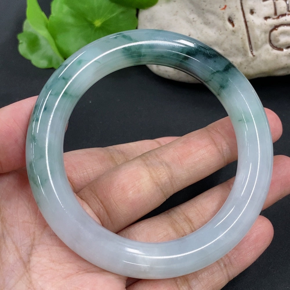HKHQ jadeite round bangle, size 54.9, weighing approx. 65.2g, featuring vibrant green jade with mineral components visible.
