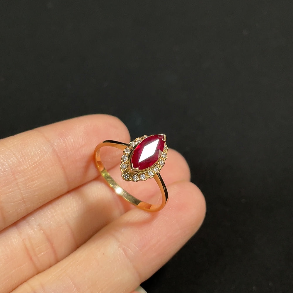 18K gold ruby ring with diamond accents, featuring a polished gold band and sparkling gemstones.