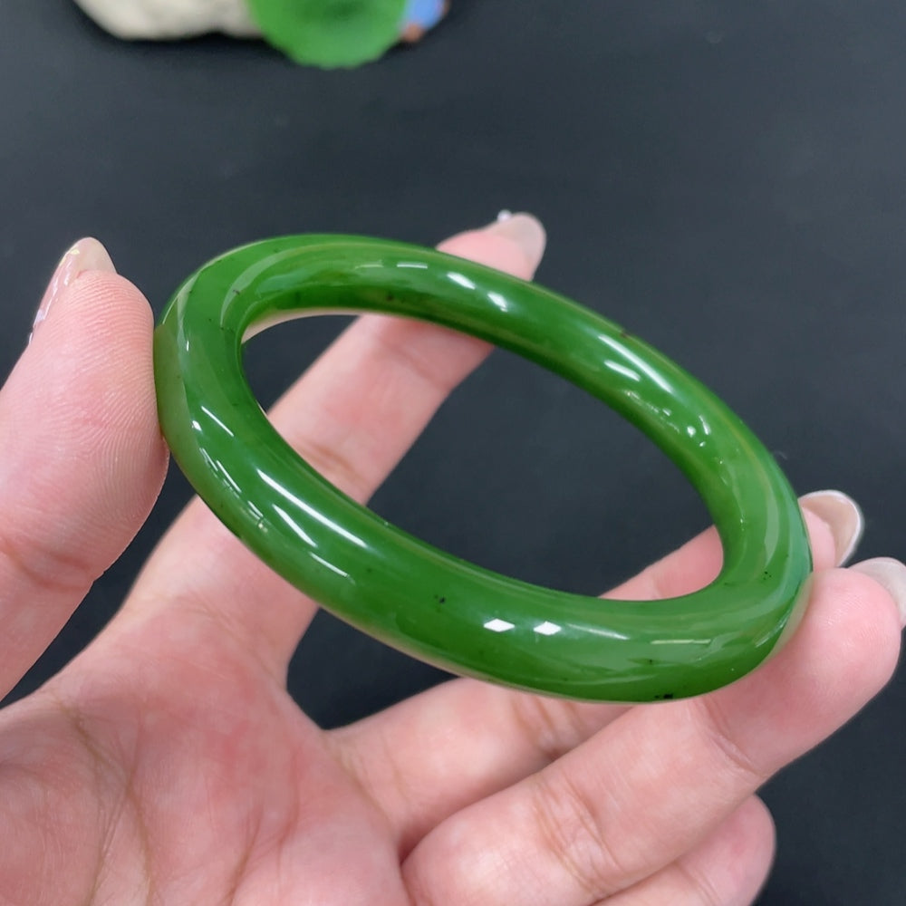 Huiliu certified Hetian jade round bangle showcasing smooth, polished green jade with natural variations and a glossy finish.