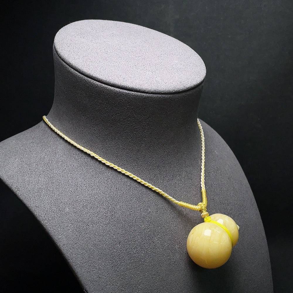 Amber beeswax pendant by HUILIU HQ with visible repair, showcasing warm amber color and handcrafted details.