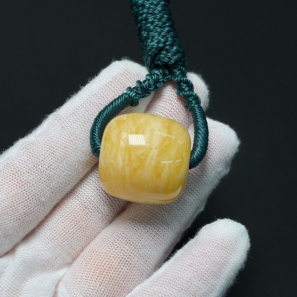 Amber beeswax pendant from HKHQ with natural amber color, weighing approximately 10.99g, displayed with a cord.