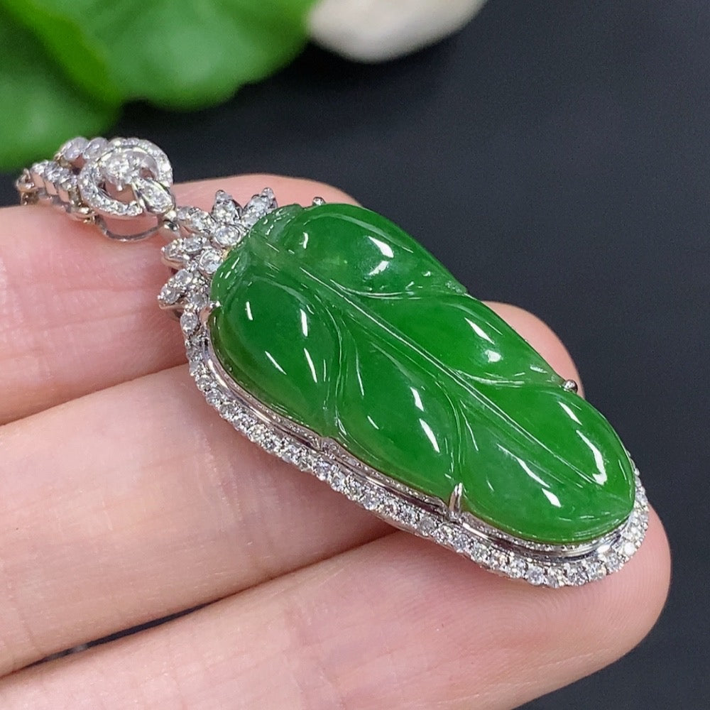 Jadeite leaf pendant with 18K gold accents and diamond details, displayed on a chain, showcasing intricate craftsmanship.