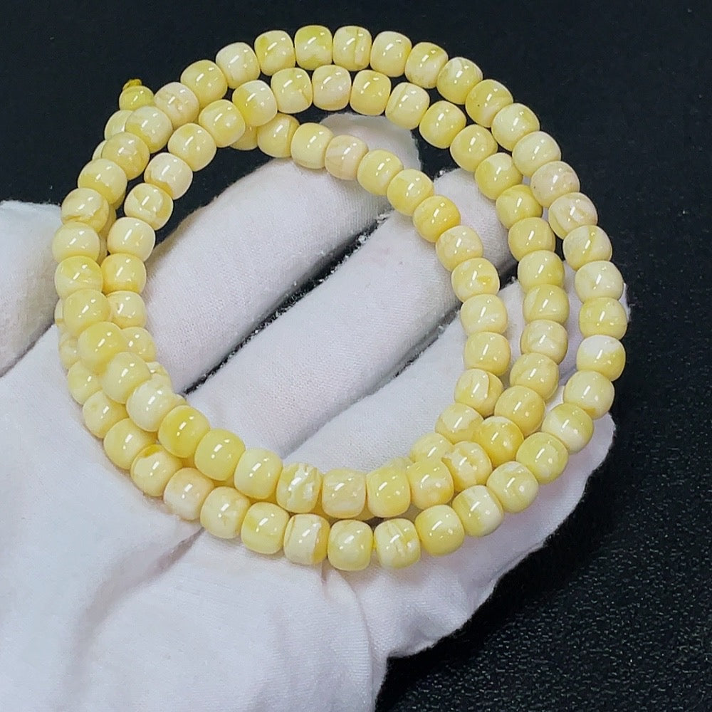 Amber beeswax gemstone bead strand, 7.3mm diameter, HKHQ brand, with approx. 25.24g weight, close-up of amber-colored beads.
