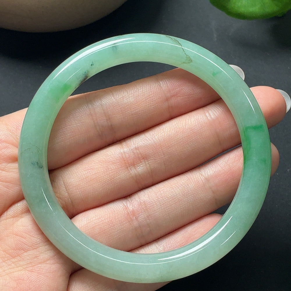 Round jadeite bangle from HKHQ featuring smooth, polished jade with a vibrant green hue, showcasing traditional jewelry craftsmanship.