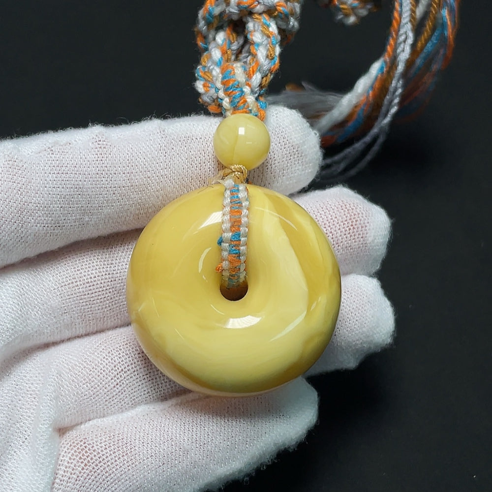 Amber beeswax pendant with natural amber color and textured surface, attached to a cord, weighing approximately 20.21 grams.