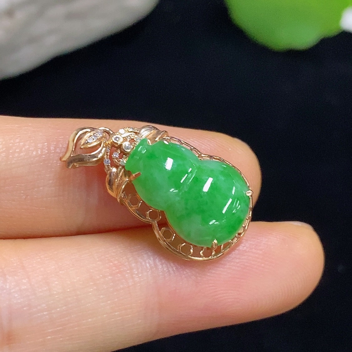 Jadeite gourd pendant with 18k gold and diamond accents, showcasing intricate inlay and polished jade surface.