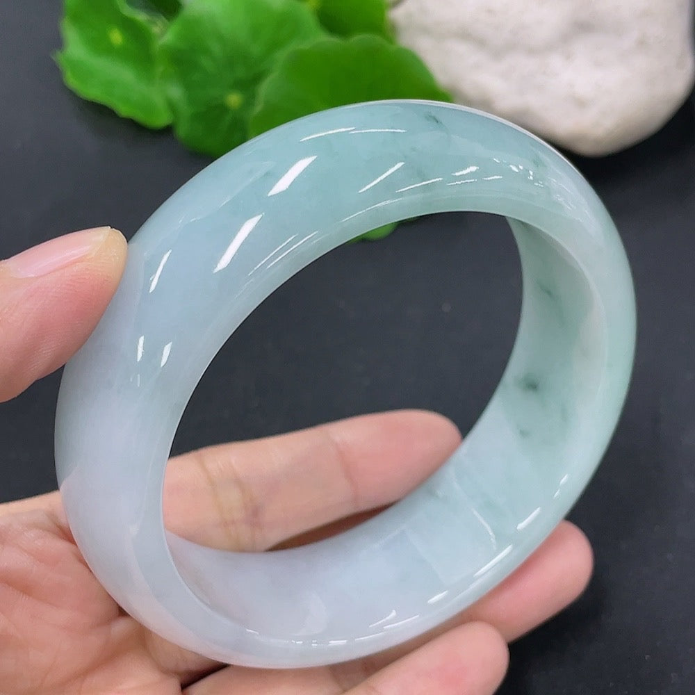 Jadeite round bangle in size 59.5mm, weighing approximately 100.43g, showcasing smooth, polished jade surface with rich green color.