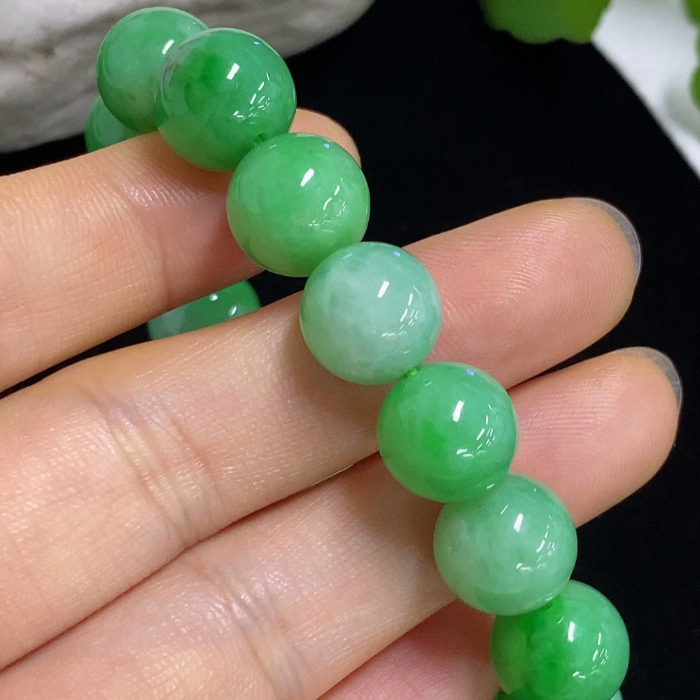 HKHQ jadeite bracelet with 11mm jade beads, approximately 43g, showcasing smooth, polished green jade stones on a neutral background.