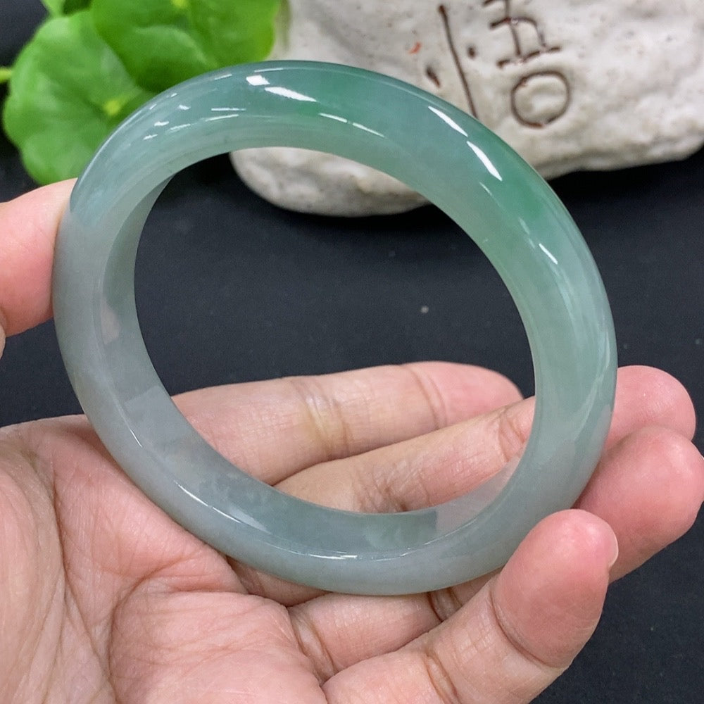Round jadeite bangle by HKHQ, size 55.5, weighing 53.26g, showcasing smooth, polished jadeite surface on a white background.