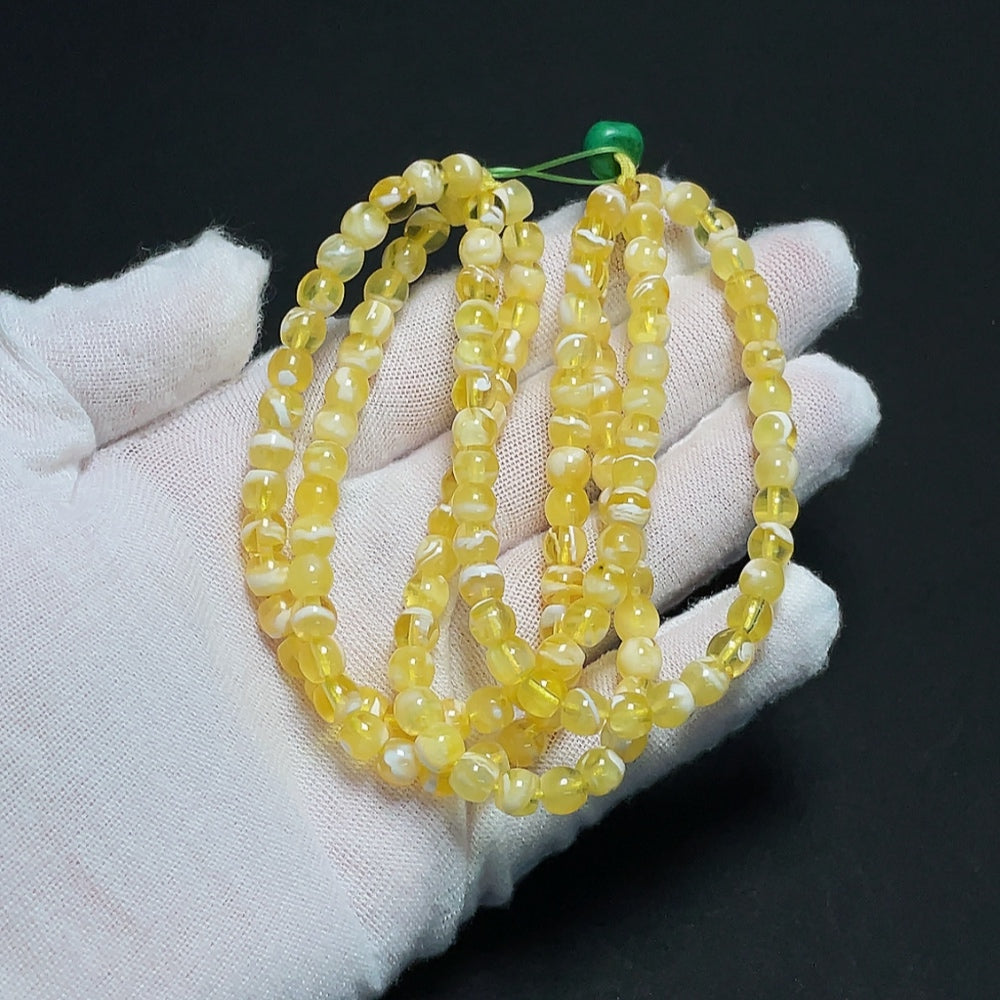 Amber HKHQ beeswax bead strand with 5.5mm amber beads and non-natural accent stones, weighing approx. 14.32g.