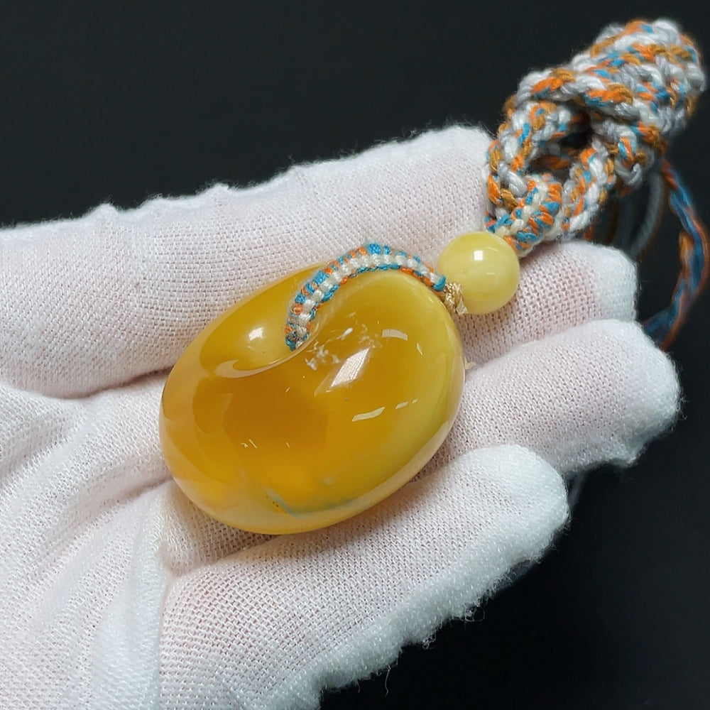 Amber beeswax pendant with natural amber stone and cord, weighing approximately 20.21 grams, by HKHQ.