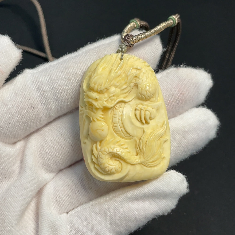 Amber beeswax pendant with natural golden hue, featuring gemstone detailing, attached to a rope for jewelry wear.