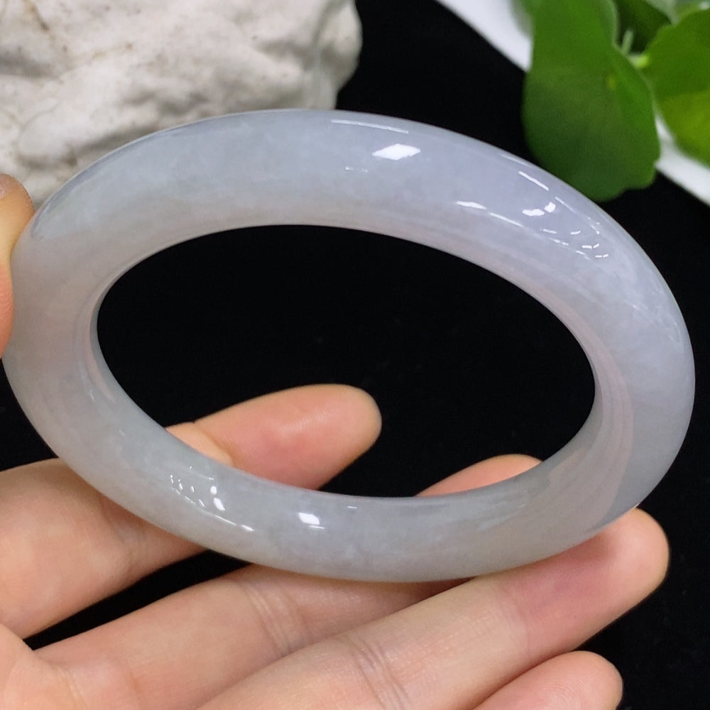 Smooth round jadeite bangle from HKHQ with a polished surface, showcasing its vibrant green color and elegant circular design.