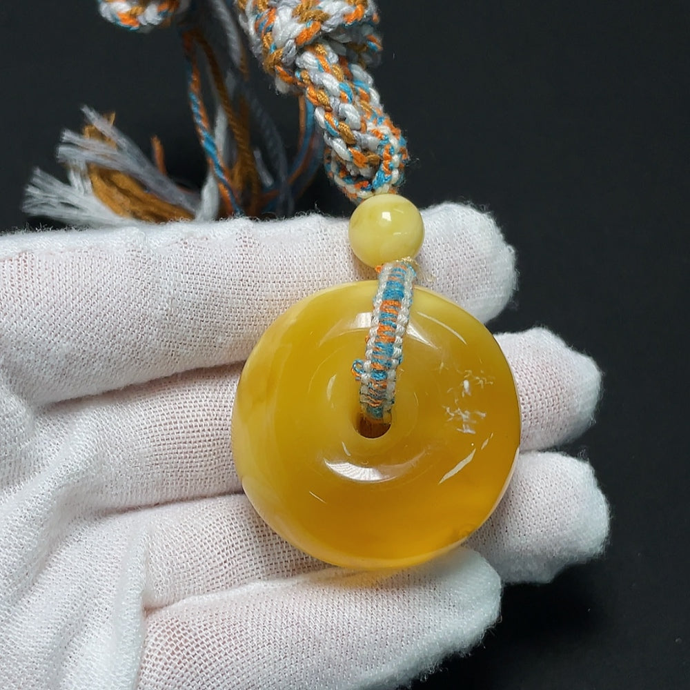 Amber beeswax pendant with cord, handcrafted HKHQ jewelry, showcasing warm amber hue and natural textured surface.