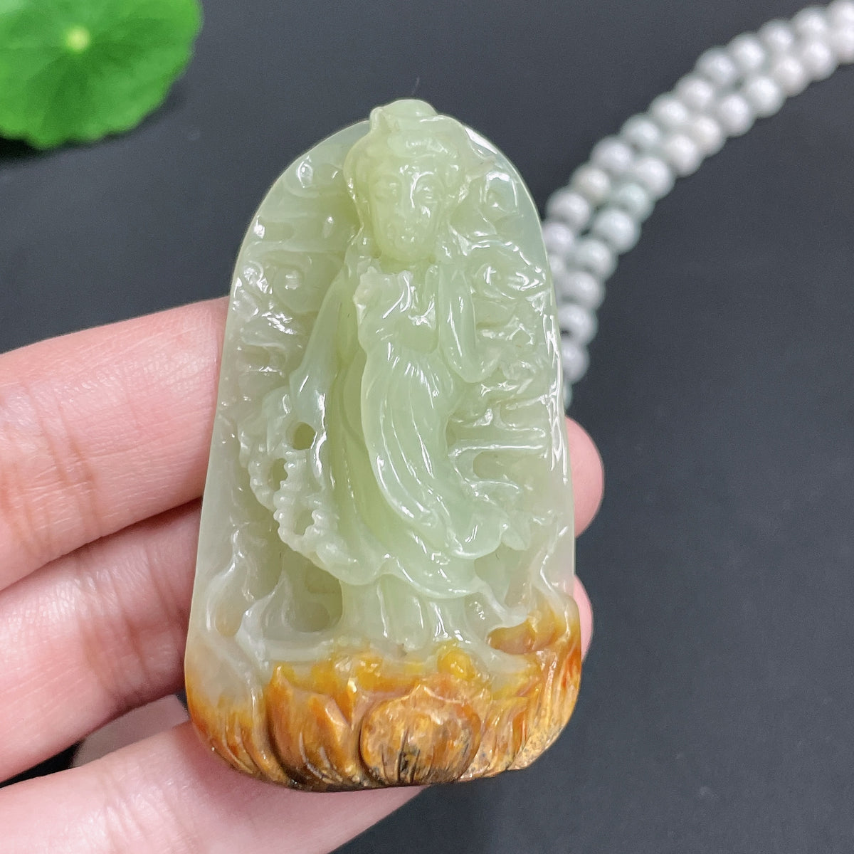 Huiliu certified Khotan jade pendant featuring Guanyin figure on chain, showcasing smooth green jade with natural stone texture.